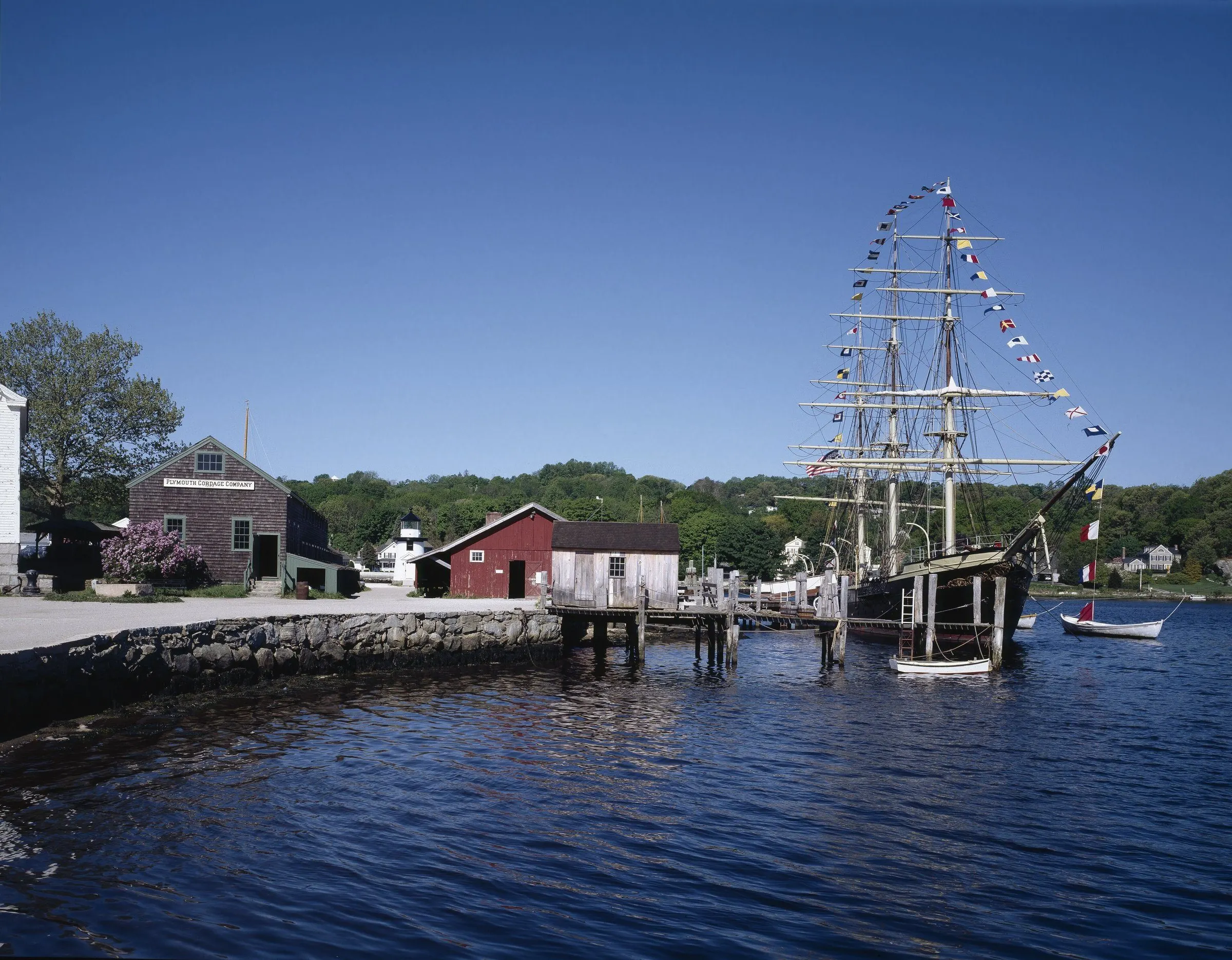 The whaling ship Charles W. Morgan, flags flying, moored on the Mystic River at Mystic Seaport