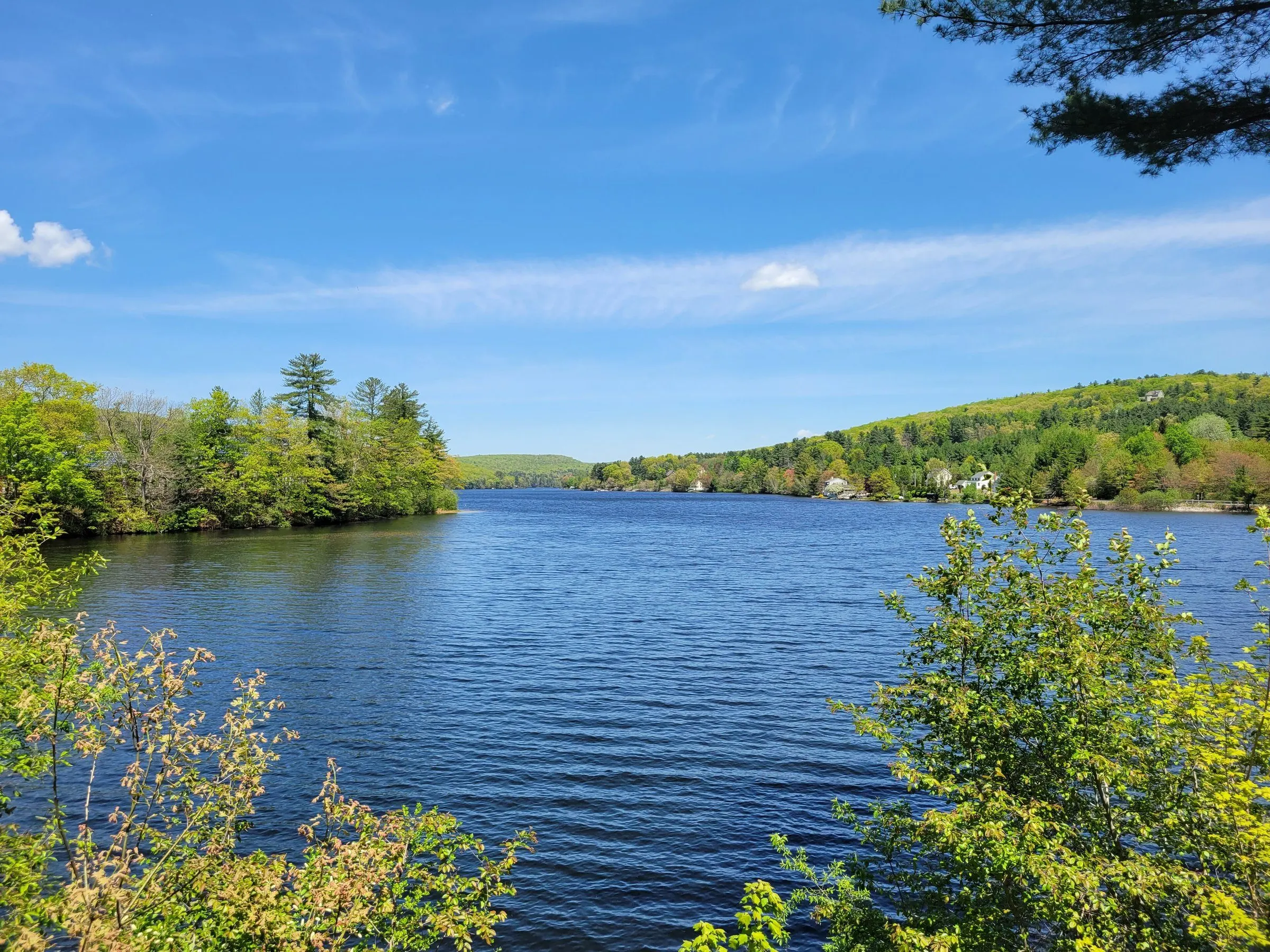 Staffordville Lake in spring, blue water between green wooded hills under a clear sky