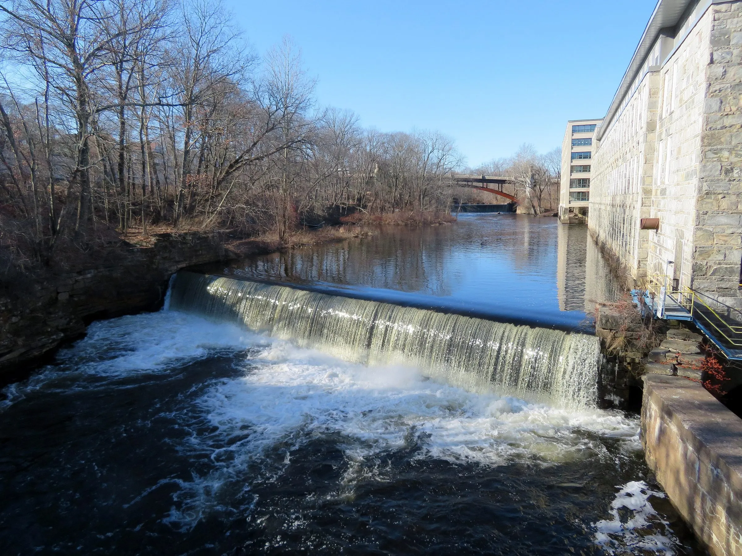 The Willimantic River flowing over the dam beside the stone Jillson mill in Willimantic